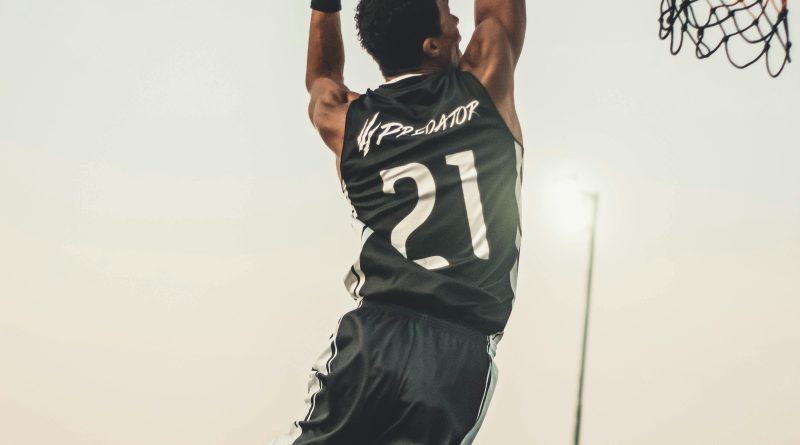 A dynamic basketball player executing a slam dunk during a vibrant outdoor game.